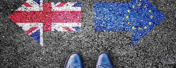Aerial view of a pair of men's brogues againt a tarmac background with the British and European Union flags visible on either side