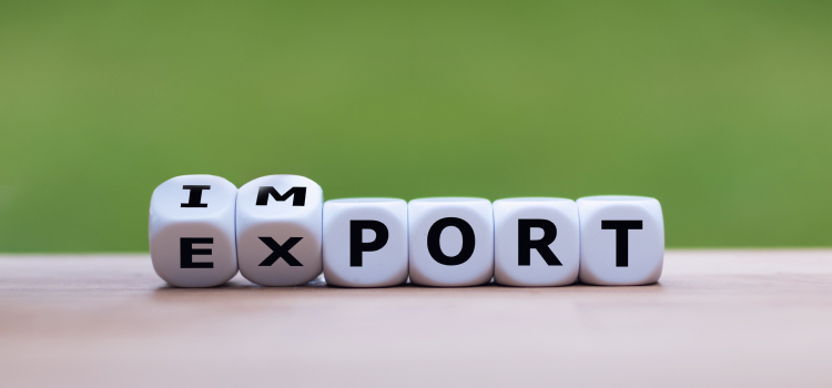 : Dice letters spell the words “import” and “export” on a wooden table with a green background